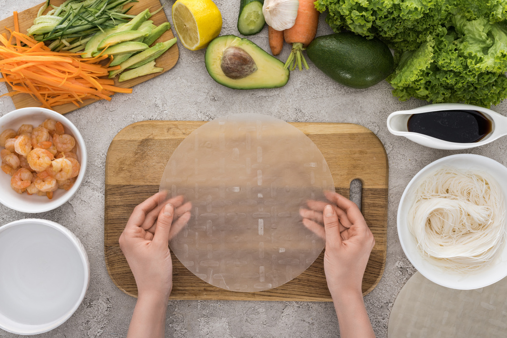 top view of woman putting rice paper on cutting board  - Photo, Image