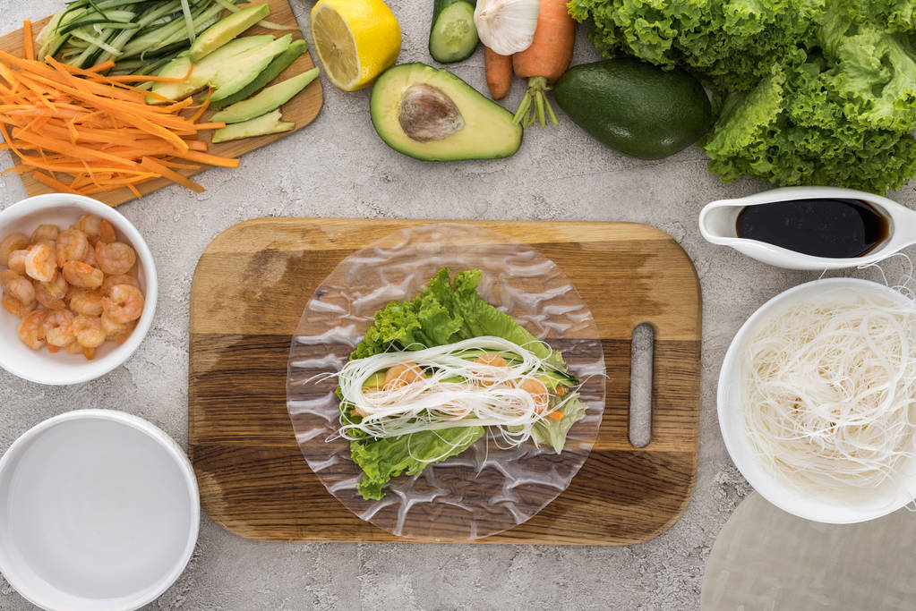 vista superior de camarões, alface e macarrão sobre papel de arroz, sobre tábua de corte
  - Foto, Imagem