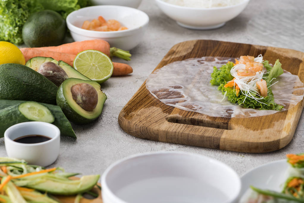 cut carrot, lettuce, noodles, shrimps and rice paper on cutting board  - Photo, Image