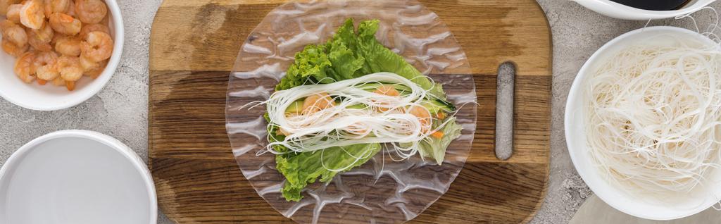 panoráma-shot garnélarák, fejes saláta és nudli rizspapír, vágódeszka  - Fotó, kép