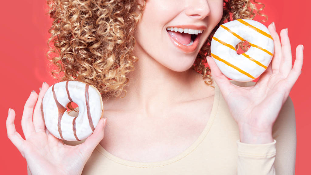Kaunis nuori iloinen tyttö puree donitsi
 - Valokuva, kuva
