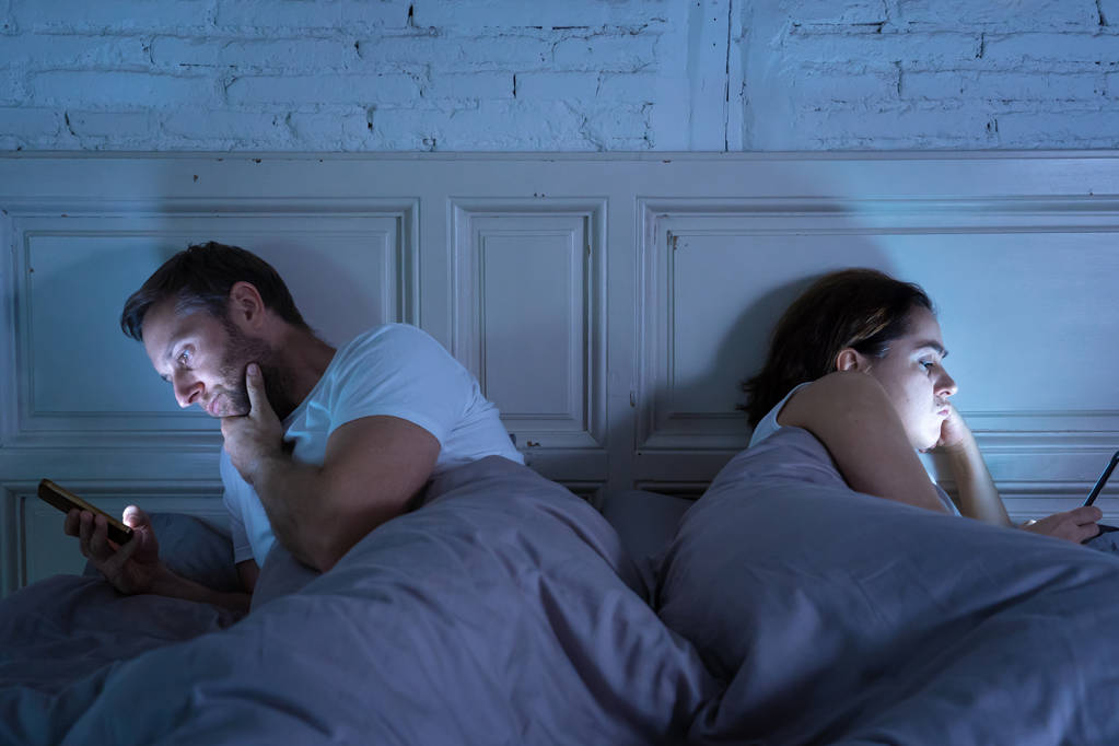 Νεαρό ζευγάρι στο κρεβάτι αργά τη νύχτα, χρησιμοποιώντας έξυπνα τηλέφωνα εμμονή με παιχνίδια, social media και εφαρμογές αγνοώντας κάθε άλλη σχέση προβλήματα επικοινωνίας και έννοια κινητό εθισμού στο διαδίκτυο. - Φωτογραφία, εικόνα