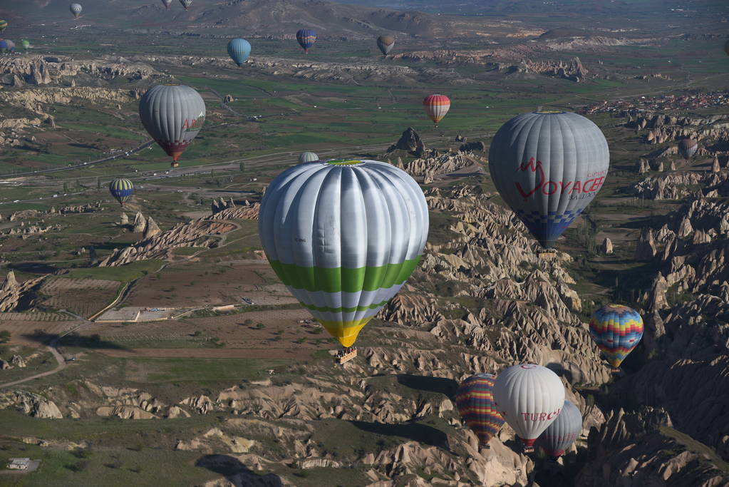 Panoramablick auf ungewöhnliche Felslandschaft in Kappadokien, Türkei. Bunte Heißluftballons fliegen in den Himmel über tiefen Schluchten, Tälern und Feenschornsteinen der Region Kappadokien.  - Foto, Bild