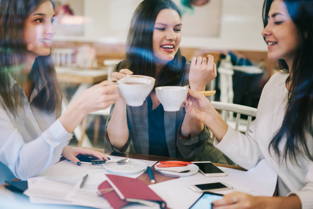 Pozitivní veselý hipster dívky jásající s hrnky kávy během přestávky pro socializaci během spolupráce na start-up projektu pocit dobré formy přátelství, koncepce, pokud komunikace - Fotografie, Obrázek