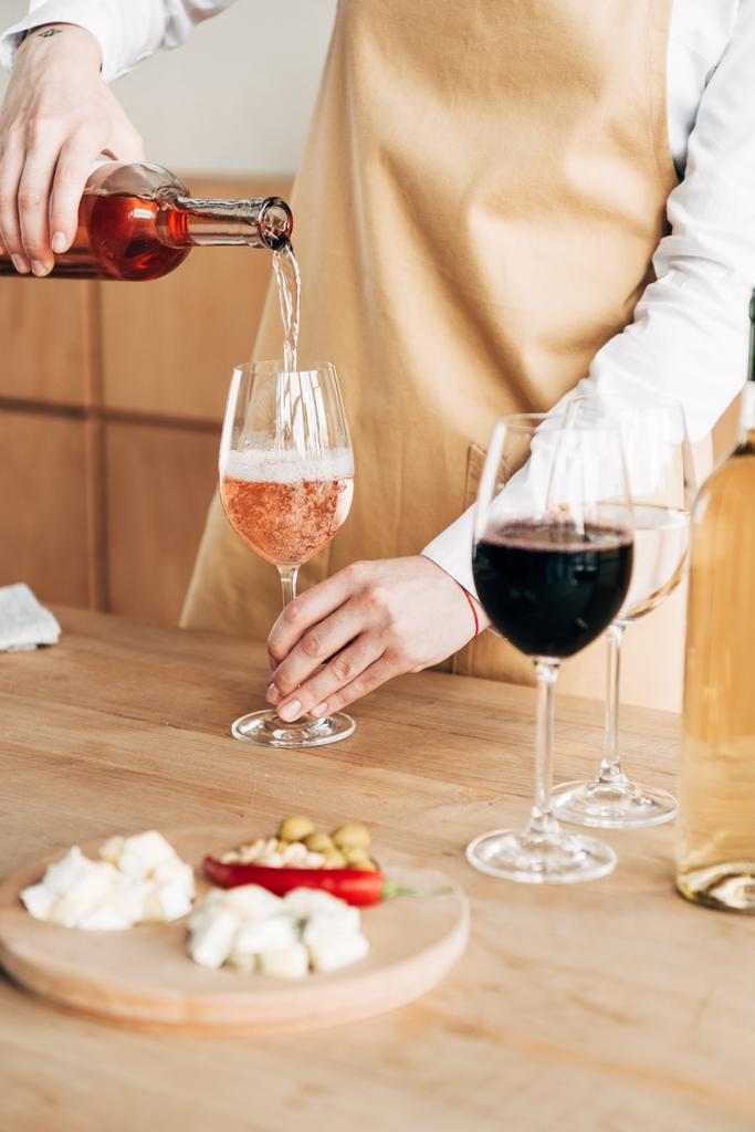 częściowy widok sommelier w butelce trzymając butelkę i nalewanie wina w kieliszek do wina - Zdjęcie, obraz
