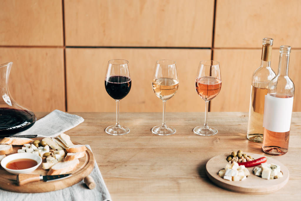 Kieliszki do wina, butelki wina i jedzenie na drewnianym stole - Zdjęcie, obraz