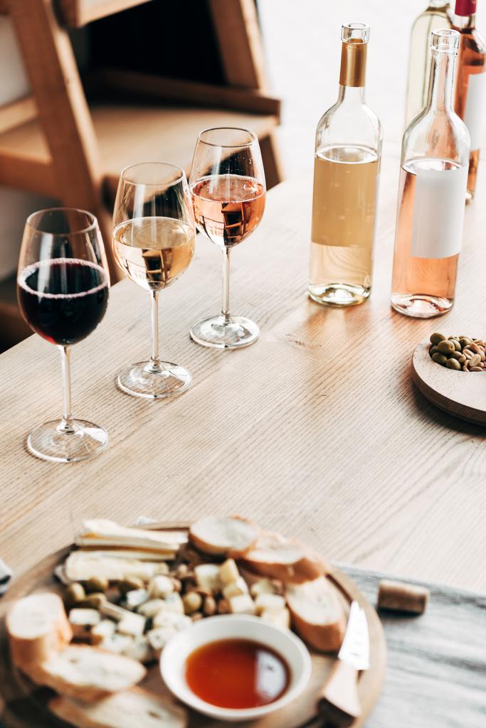 ποτήρια κρασιού, μπουκάλια κρασιού και φαγητού σε ξύλινο τραπέζι - Φωτογραφία, εικόνα