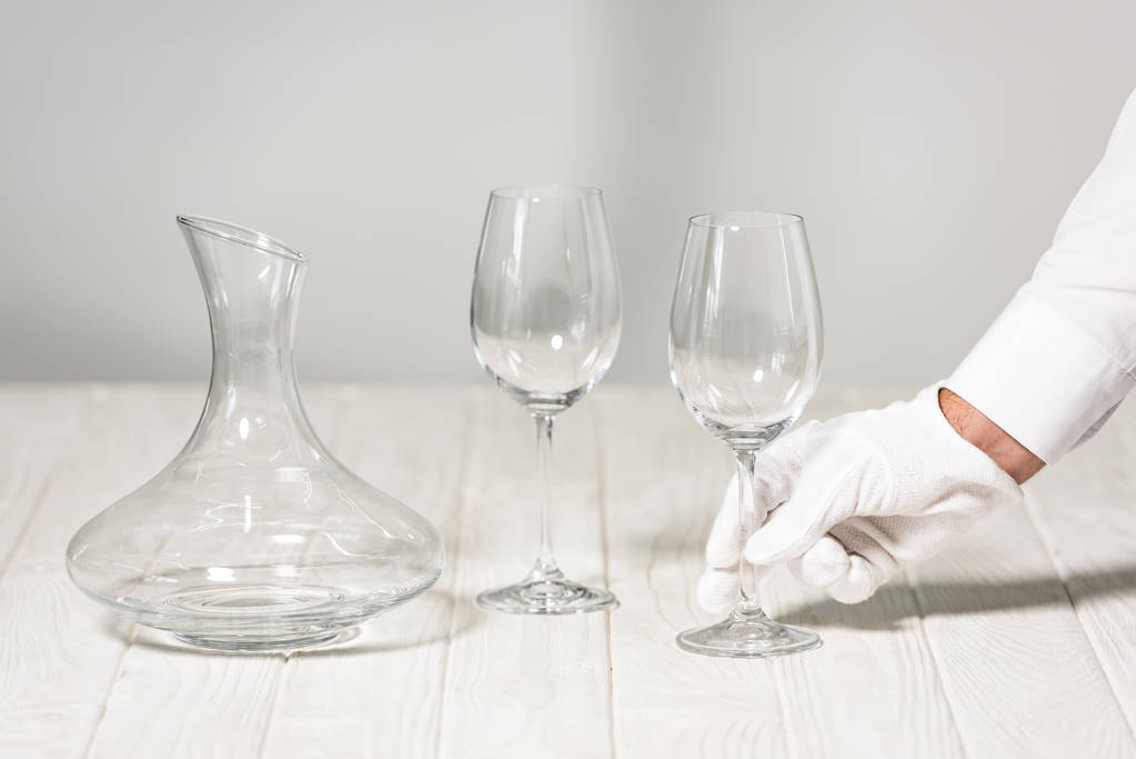 частичный вид официанта с пустым бокалом вина в ресторане
 - Фото, изображение