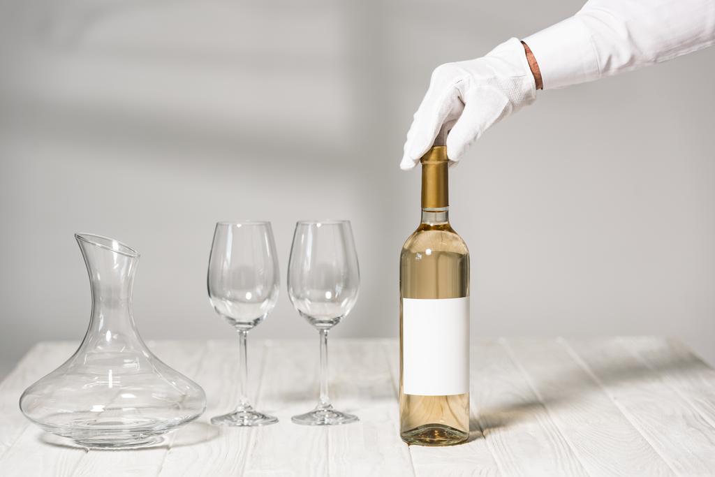 частичный вид официанта, держащего бутылку вина в ресторане
 - Фото, изображение