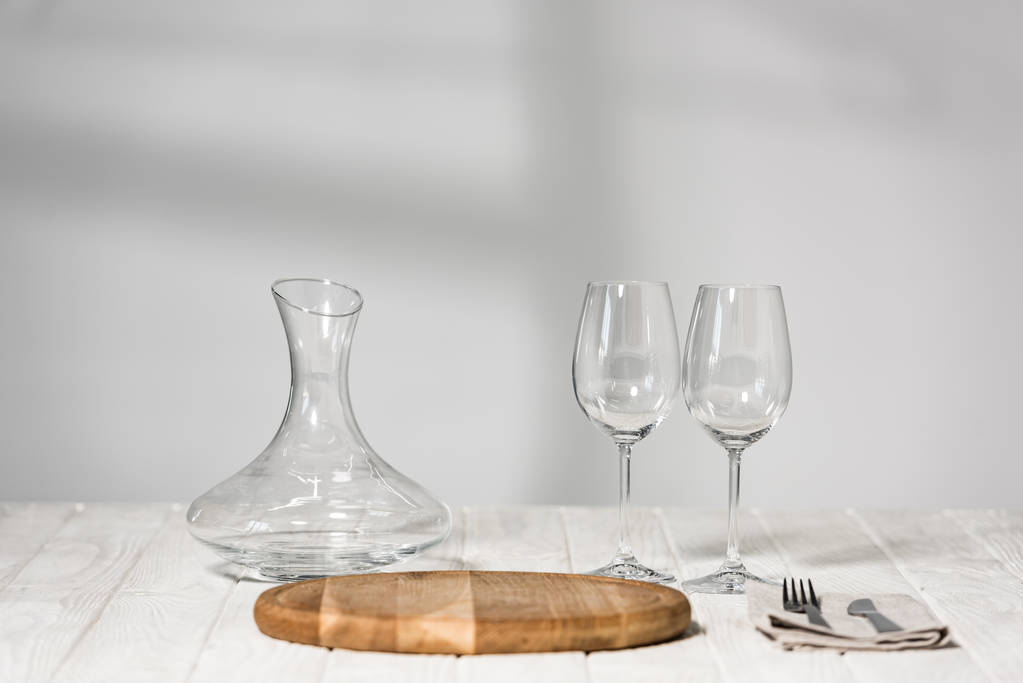 jug, wine glasses, cutlery and cutting board on wooden surface in restaurant - Photo, Image