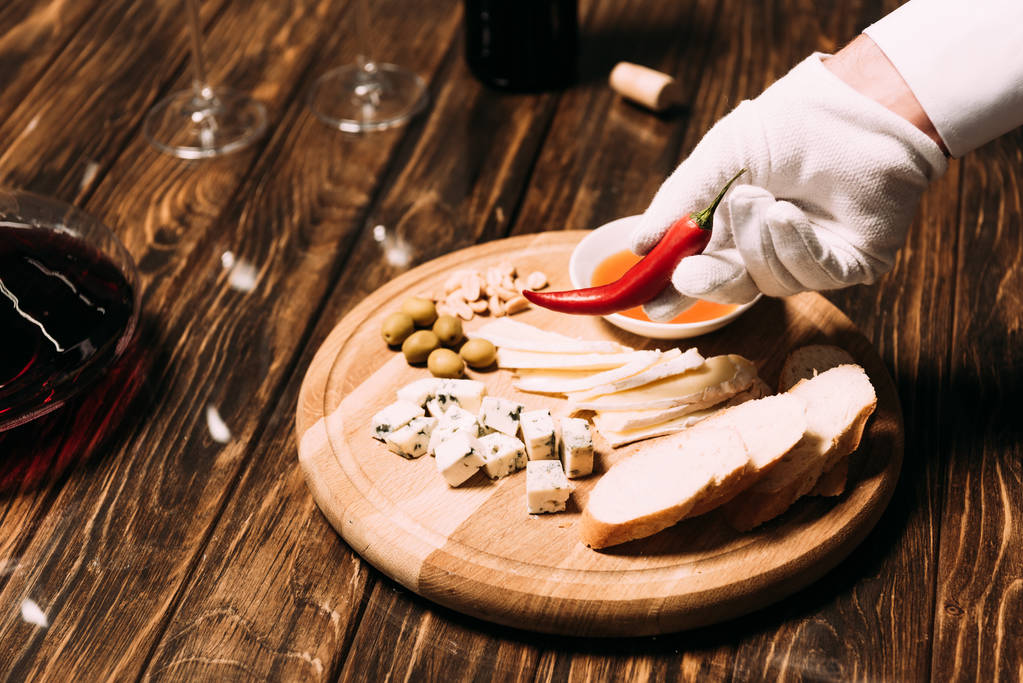 vista ritagliata del cameriere in guanto bianco che tiene pepe vicino alla tavola con cibo e vino
 - Foto, immagini