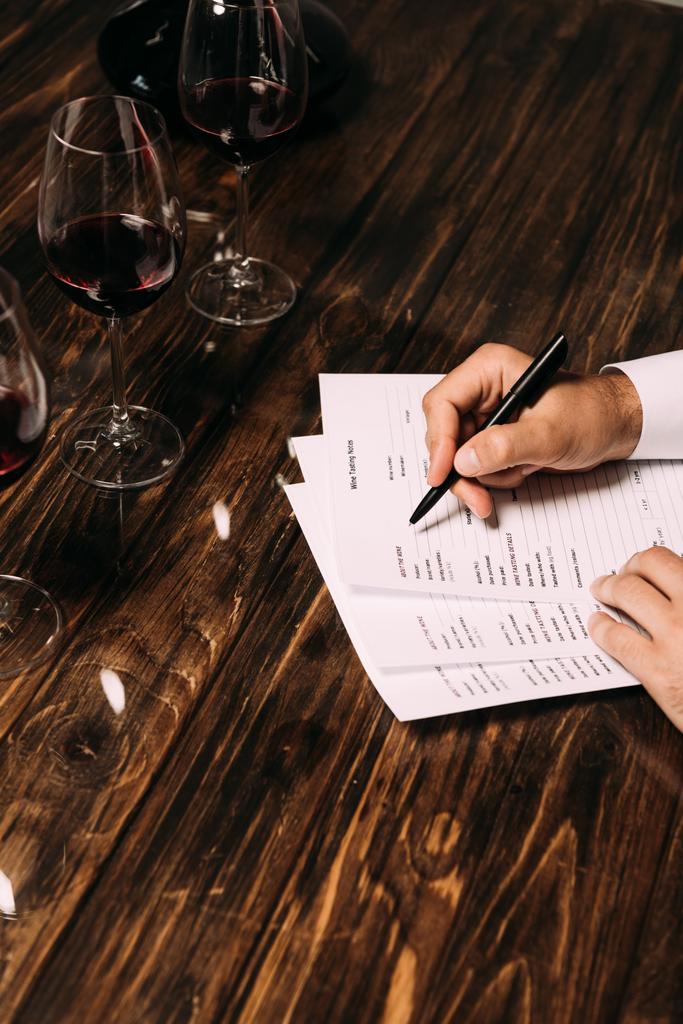 partial view of sommelier writing at table with wine glasses - Photo, Image