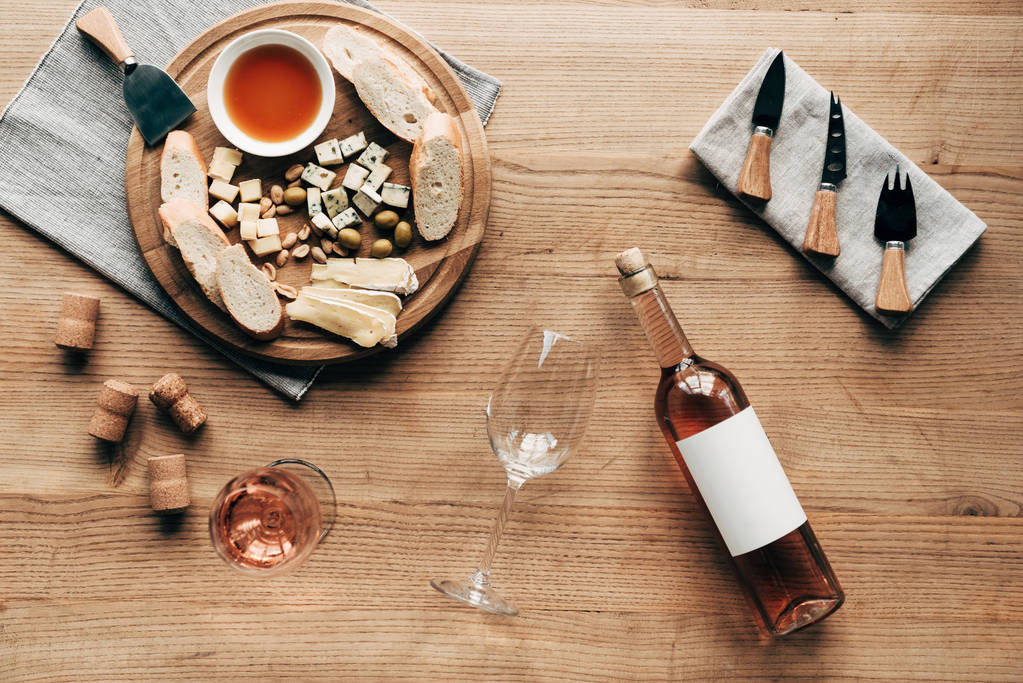 vista superior de copas de vino, botella de vino, salsa, pan, queso, aceitunas, corchos y utensilios de cocina en la superficie de madera
 - Foto, Imagen