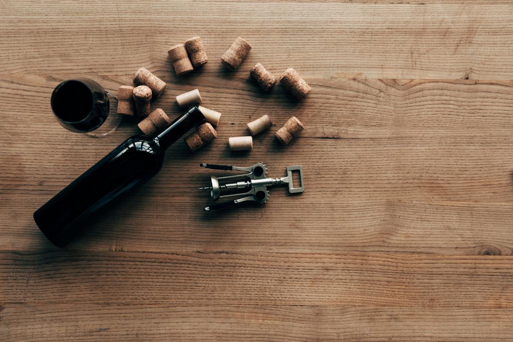 vista dall'alto di bottiglia di vino, bicchiere di vino, tappi e cavatappi su superficie di legno
 - Foto, immagini