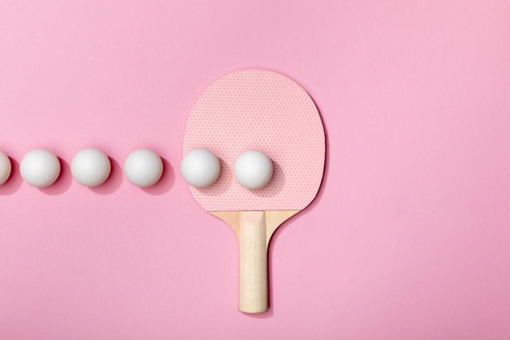 platte lay met witte Ping-Pong ballen en racket op roze achtergrond - Foto, afbeelding
