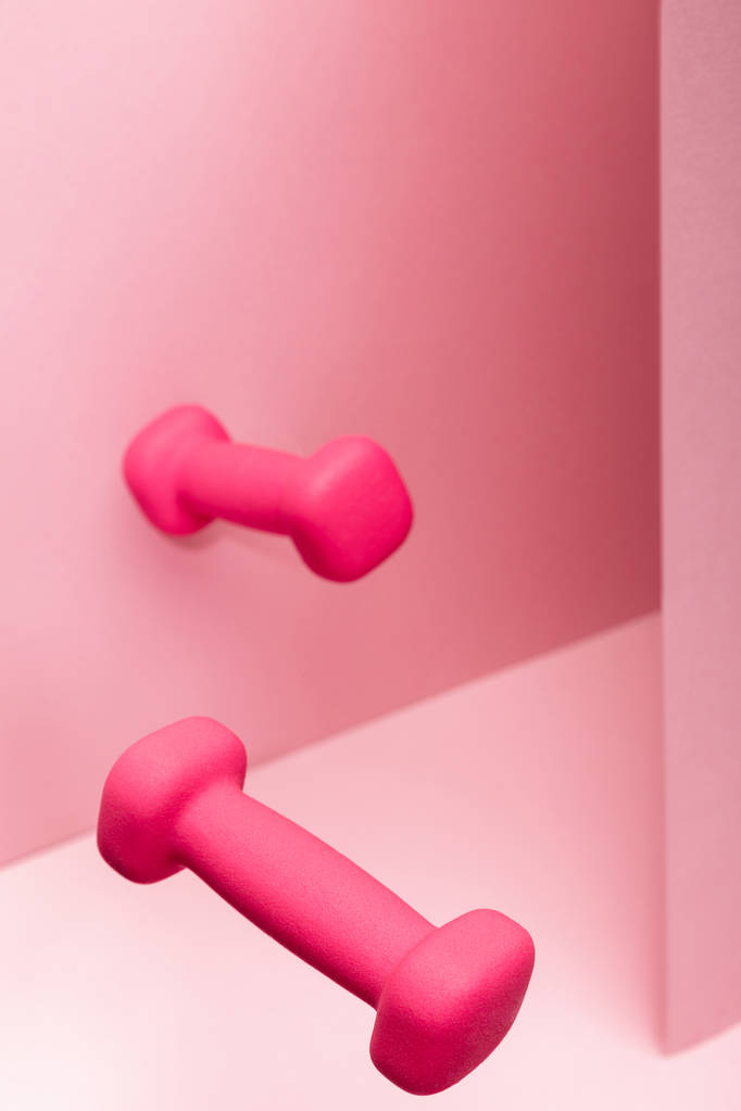 pink bright dumbbells flying in air on pink background - Photo, Image