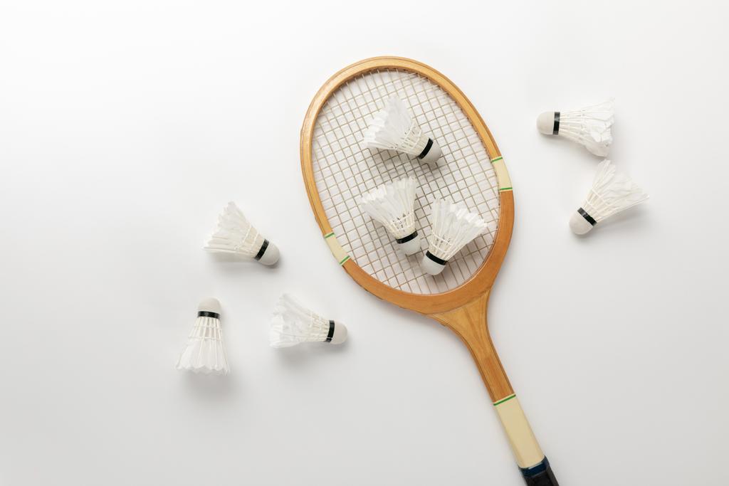 Draufsicht auf hölzerne Badmintonschläger und Federbälle auf weißem Hintergrund - Foto, Bild