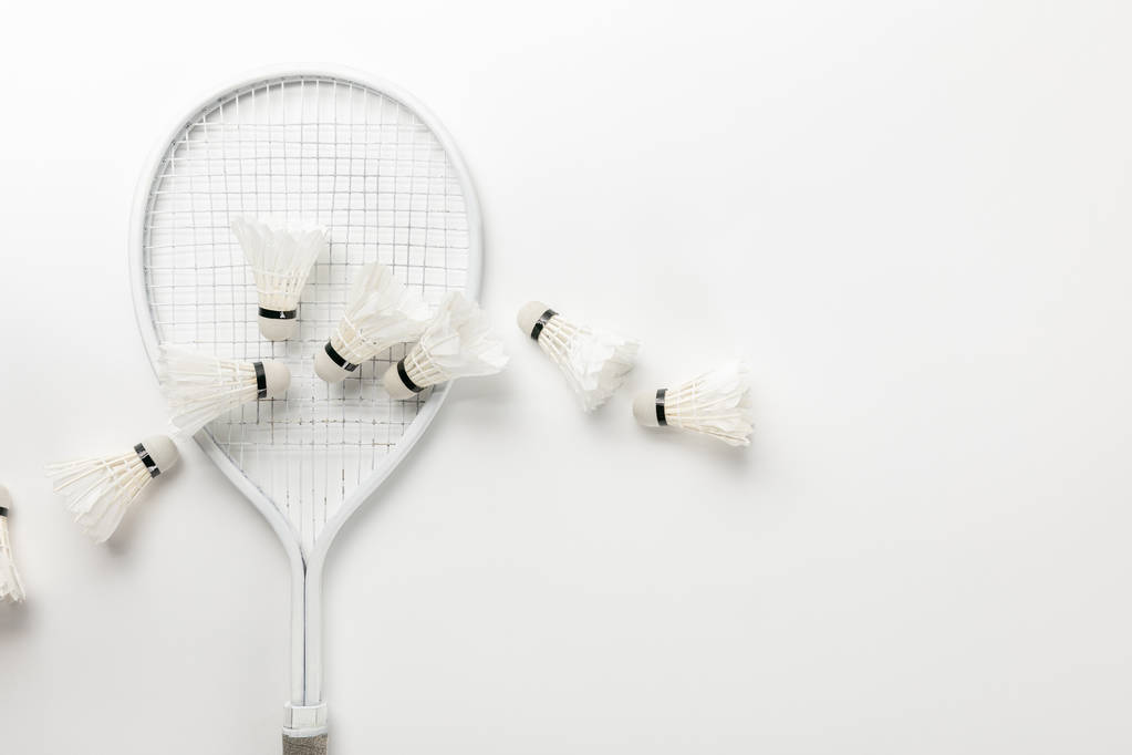 Top uitzicht van witte badminton racket en shuttle kranen op witte achtergrond - Foto, afbeelding