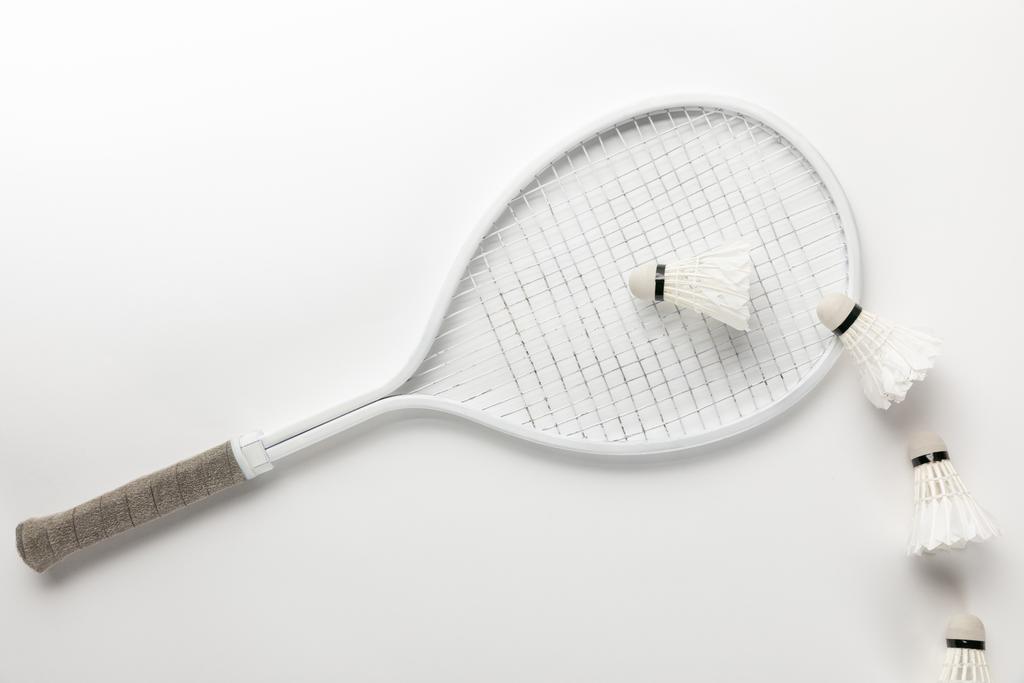 flache Liege mit weißem Badmintonschläger und Federbällen auf weißem Hintergrund - Foto, Bild