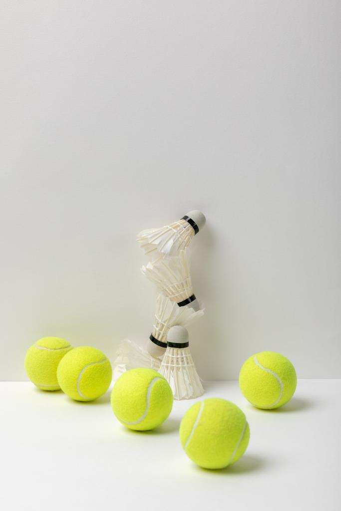 witte badminton shuttlecocks en gele tennisballen op witte achtergrond - Foto, afbeelding