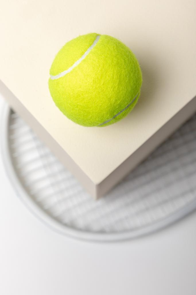 白い背景に立方体とラケット上の明るい黄色のテニスボールの選択的な焦点 - 写真・画像