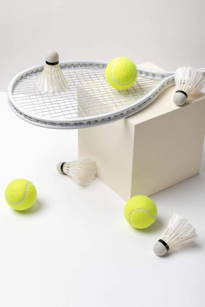 tennis racket en fel gele tennisballen met shuttle op de kubus op witte achtergrond - Foto, afbeelding