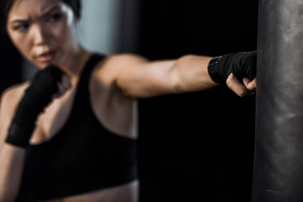 valikoiva painopiste nainen treenata lähellä nyrkkeilysäkki eristetty musta
  - Valokuva, kuva