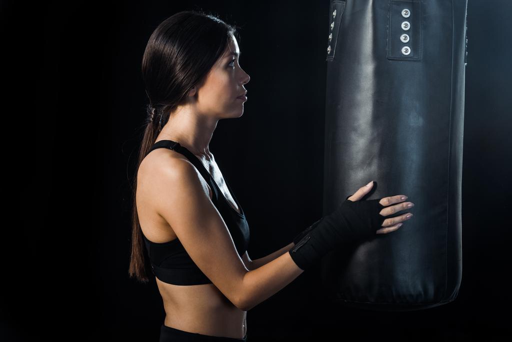 selective focus of sportswoman looking at punching bag isolated on black  - Photo, Image