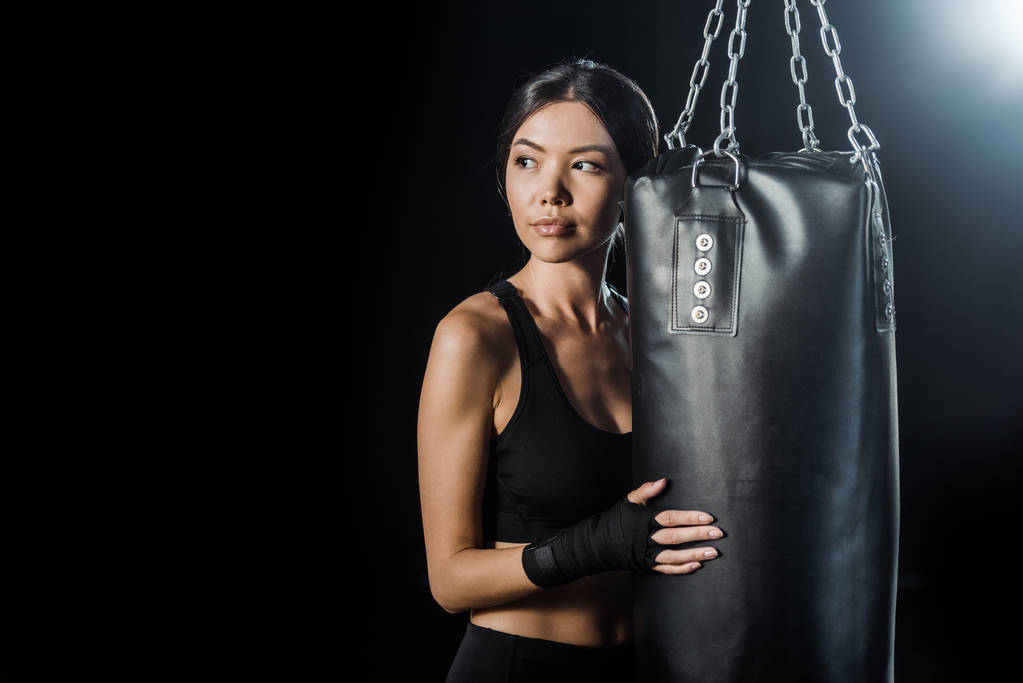young woman standing near punching bag isolated on black  - Photo, Image