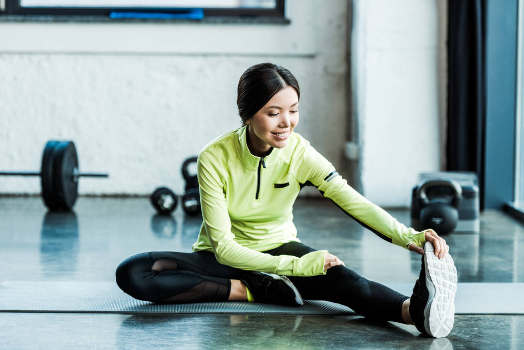 happy young woman in sportswear stretching in gym  - Photo, Image