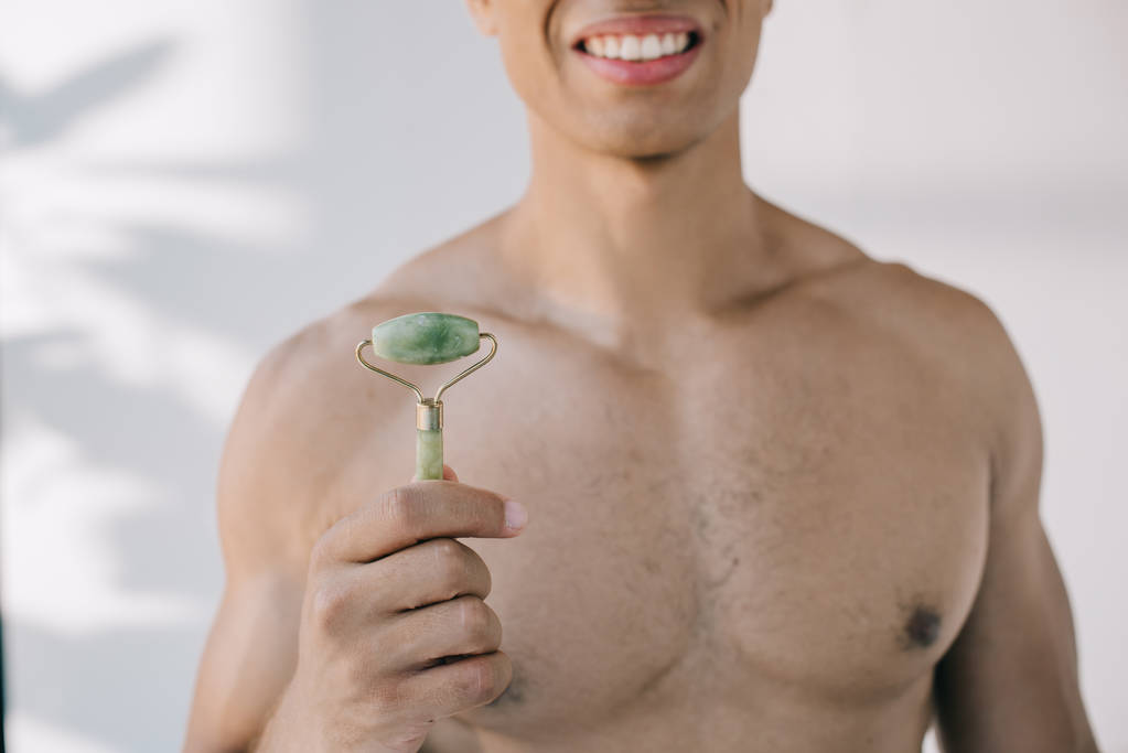 visão cortada de homem de raça mista apresentando rolo de jade de pedra e sorrindo enquanto olha para a câmera
 - Foto, Imagem