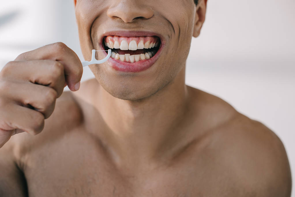 cropped view of mixed race man using dental floss on stick  - Photo, Image