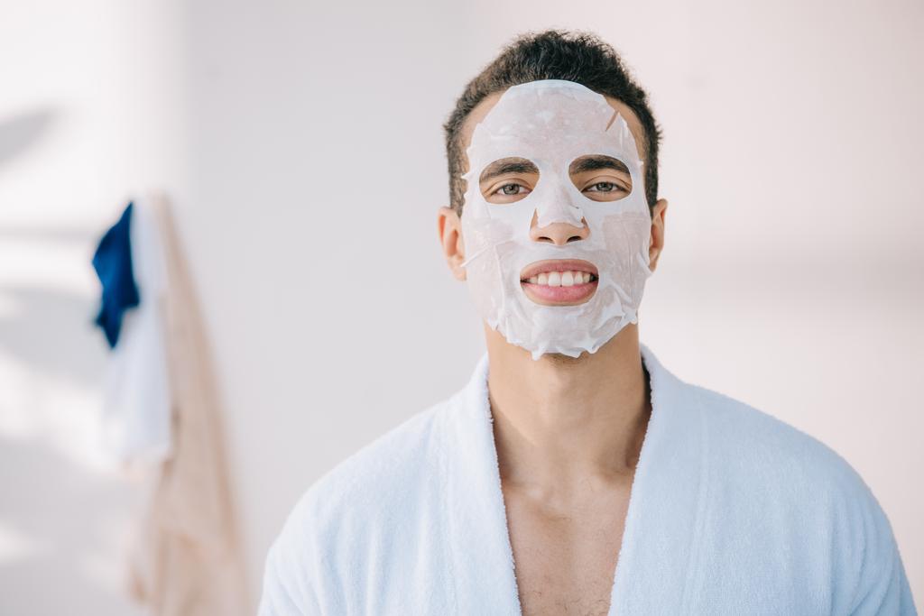 young man in bathrobe with face mask looking at camera - Photo, Image