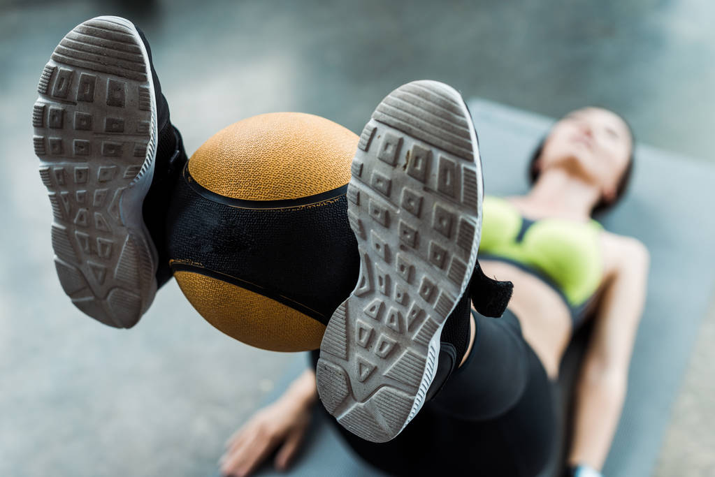 επιλεκτική εστίαση της γυναίκας άσκηση με μπάλα στο χαλάκι Fitness στο γυμναστήριο  - Φωτογραφία, εικόνα
