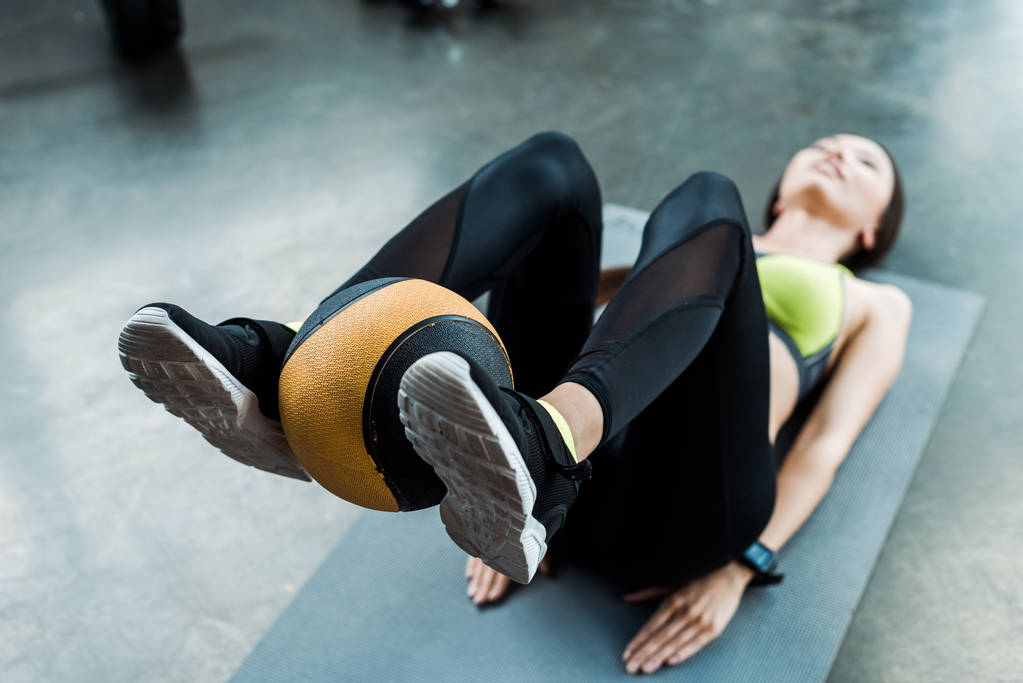 spor salonunda fitness mat üzerinde top ile egzersiz genç kadın seçici odak  - Fotoğraf, Görsel