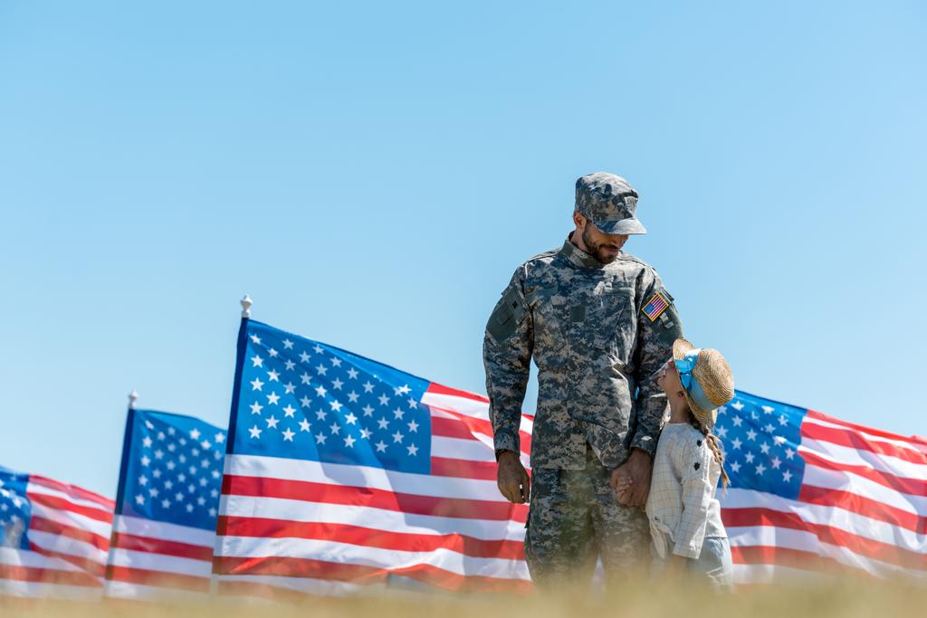 Selektiver Fokus des Militärmannes mit Mütze auf Kinder und amerikanische Flaggen  - Foto, Bild