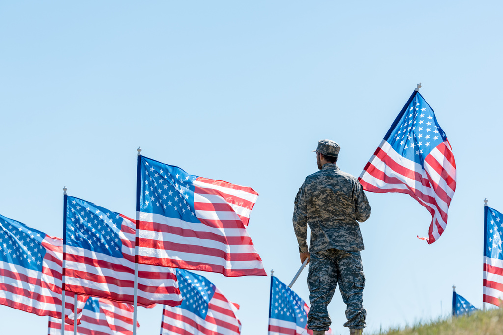 вибірковий фокус людини у військовій формі і кепці стоїть і тримає американський прапор
  - Фото, зображення