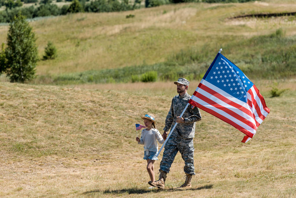 uomo militare e felice patriottico ragazzo a piedi e con bandiere americane
  - Foto, immagini