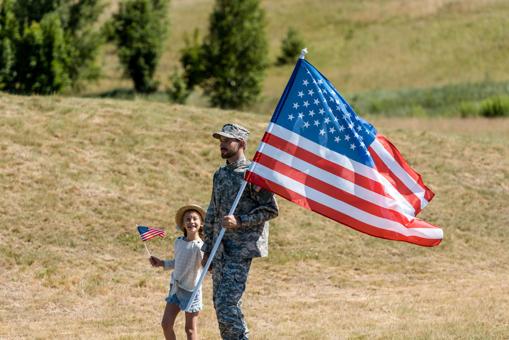 militaire man en gelukkig patriottische Kid Holding Amerikaanse vlaggen  - Foto, afbeelding