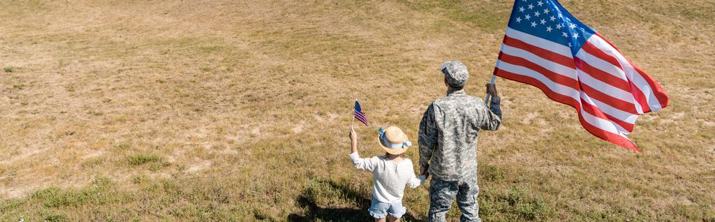 panoramic shot of military man and patriotic kid holding american flags  - Photo, Image
