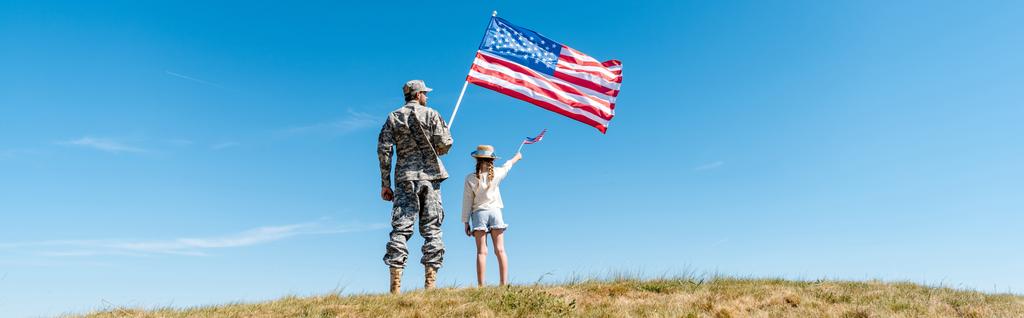panoramiczny strzał z dzieckiem i wojskowych ojciec posiadający amerykańskie flagi  - Zdjęcie, obraz