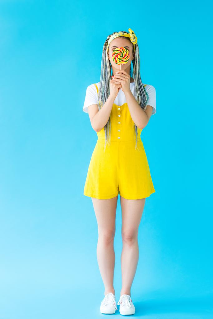 κορίτσι με ράμες που καλύπτουν το πρόσωπο με γλειφιτζούρι σε τυρκουάζ - Φωτογραφία, εικόνα