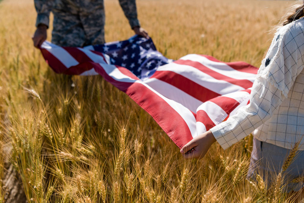 vista cortada de criança e militar homem segurando bandeira americana
  - Foto, Imagem