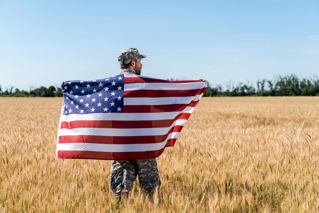 soldat en casquette et uniforme tenant le drapeau américain dans un champ d'or
  - Photo, image