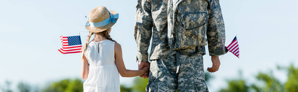 πανοραμική βολή από πατριωτικό παιδί και άνθρωπο σε στρατιωτική στολή κρατώντας τα χέρια και αμερικανικές σημαίες  - Φωτογραφία, εικόνα