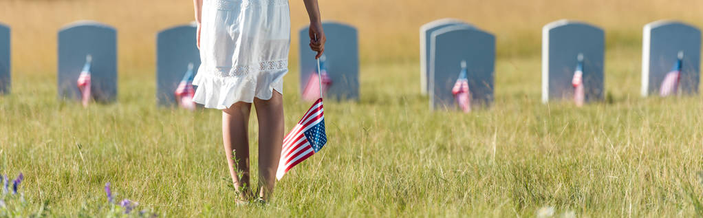 panoramatický záběr dítěte v bílých šatech na hřbitově s americkou vlajkou  - Fotografie, Obrázek