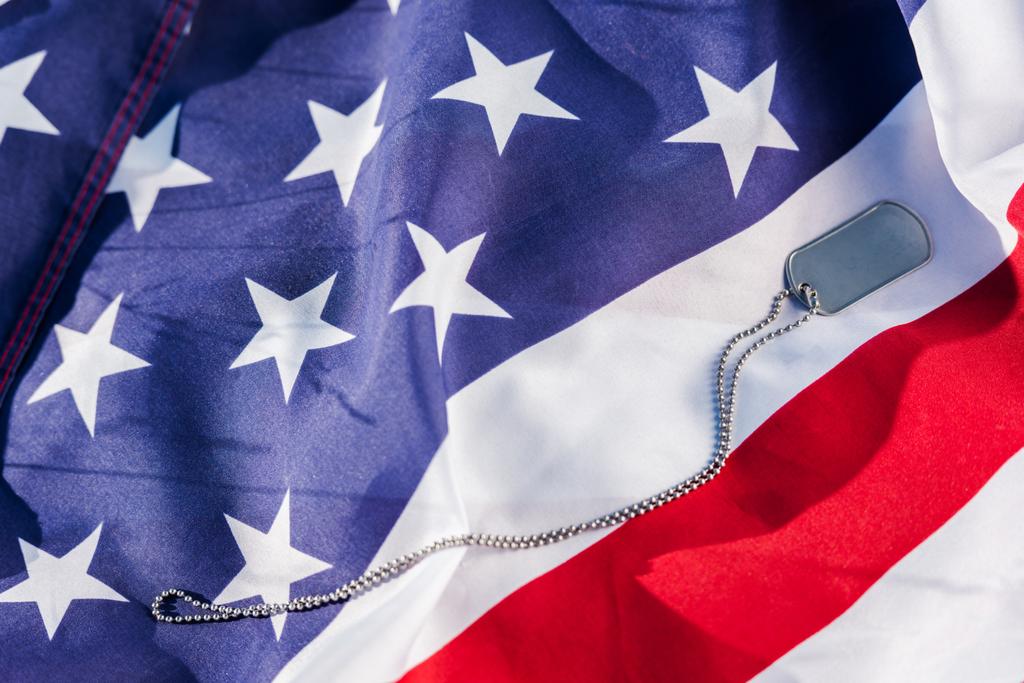 μεταλλικό σήμα στην αλυσίδα κοντά στην αμερικάνικη σημαία με αστέρια και ρίγες  - Φωτογραφία, εικόνα
