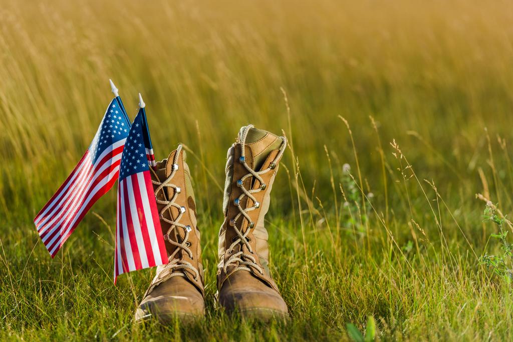Militärstiefel in der Nähe der amerikanischen Flagge mit Sternen und Streifen auf Gras  - Foto, Bild