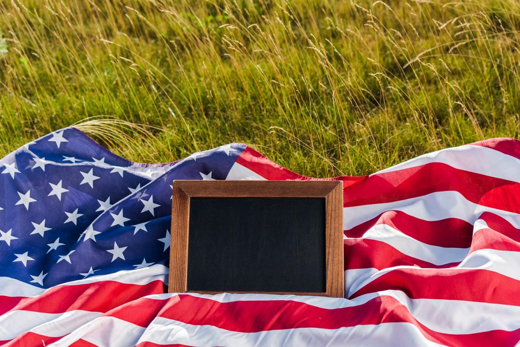 pusty tablica na amerykańskiej flagi z gwiazdami i paskami na zielonej trawie - Zdjęcie, obraz
