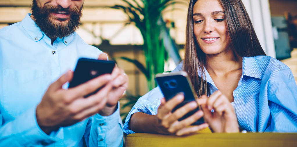 幸せな男性と女性がスマートフォンのデバイスを保持し、自由な時間の間にソーシャルネットワークでプロファイルを更新するためにデジタルガジェットを使用して、ライブ通信、男性と女性を無視して友人とのメッセージ - 写真・画像